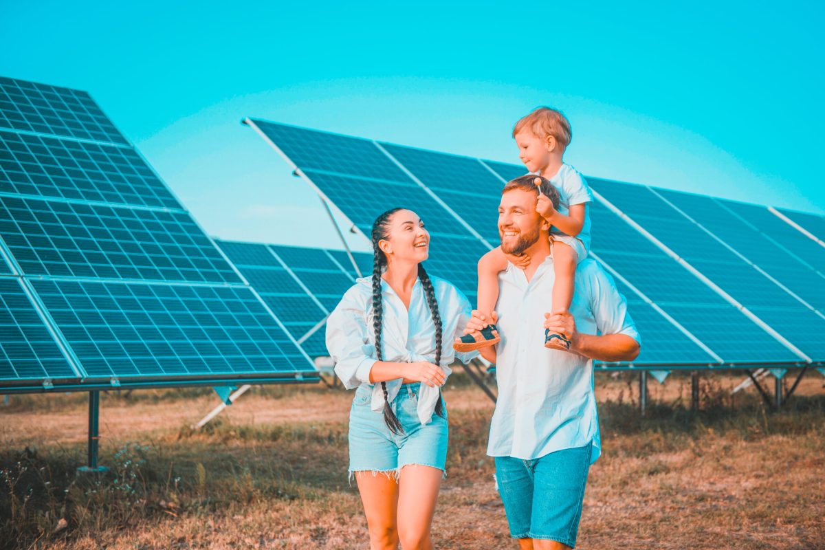 Enthusiastic father showing potential of alternative energy. Contemporary family looking at new solar station they bought. Side view of happy parents and interested child next to solar panels.